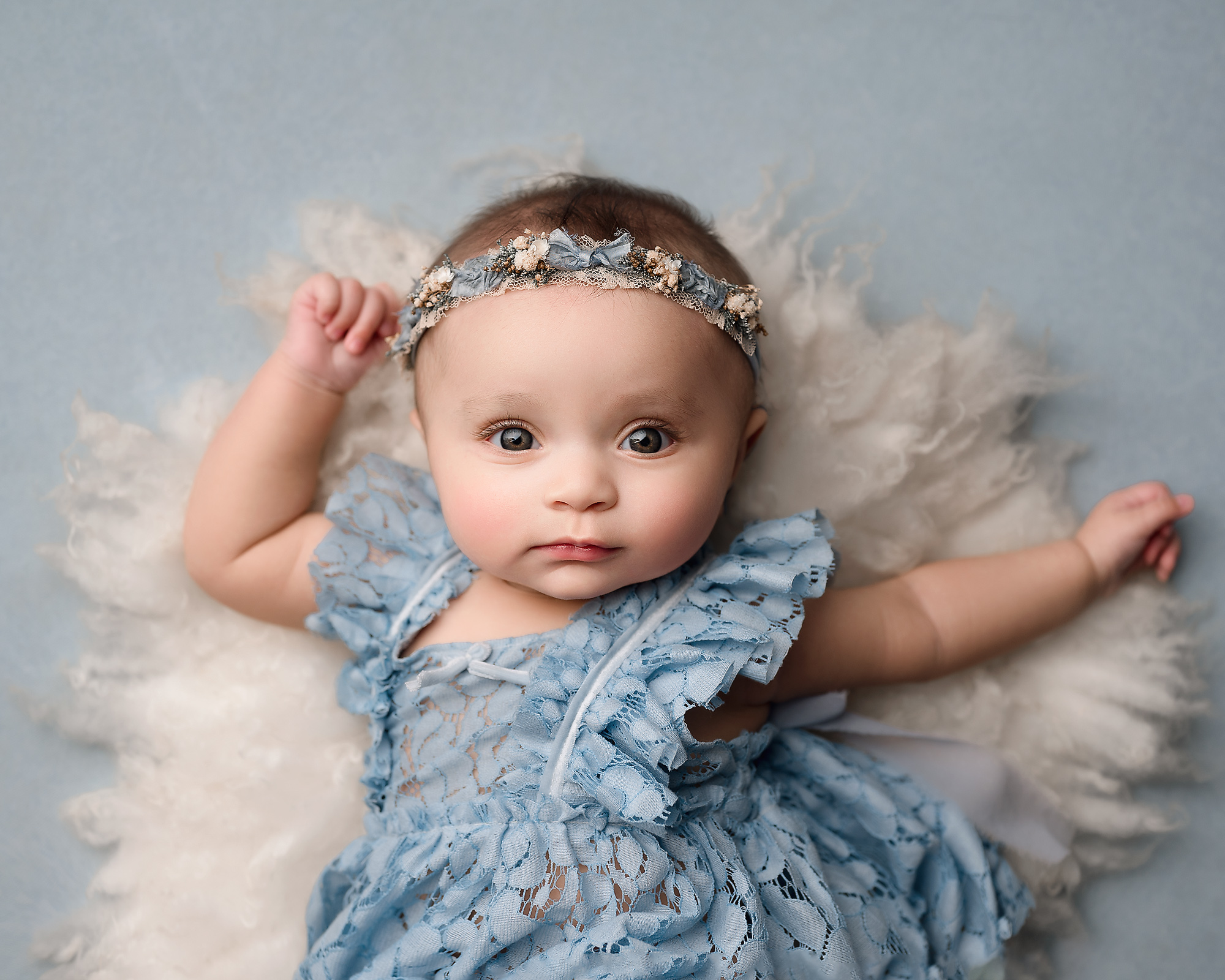 Four month old baby posing on a white fur.