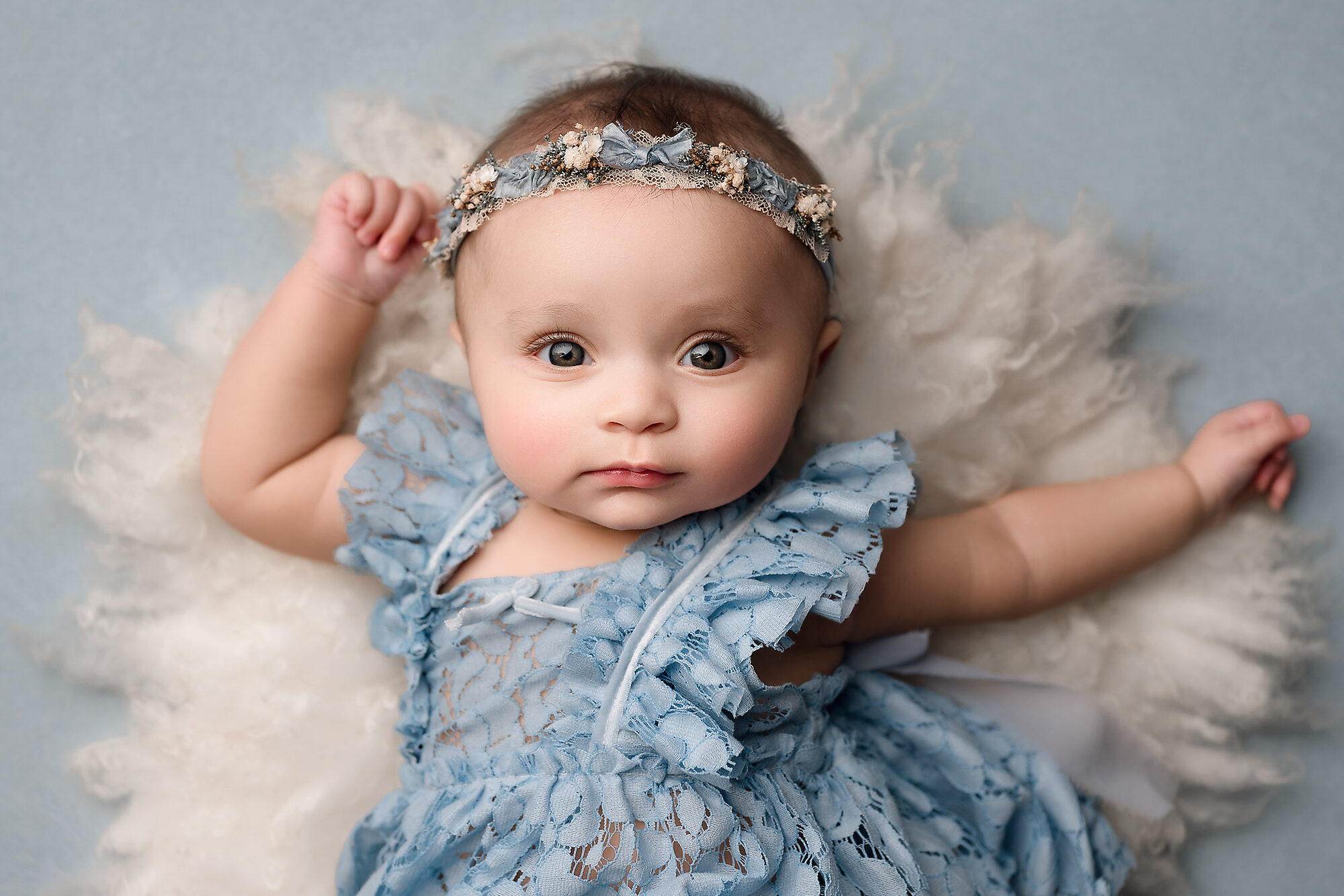 Four month old baby posing on a white fur.